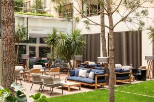 波尔多Renaissance Bordeaux Hotel的庭院设有蓝色的沙发、椅子和树木
