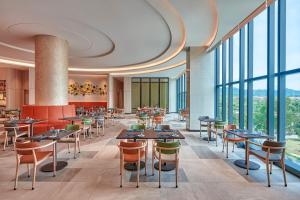 实达阿南Courtyard by Marriott Setia Alam的餐厅设有桌椅和大窗户。