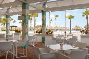 棕榈滩万豪阿鲁巴海洋俱乐部度假村的餐厅拥有白色的桌椅和棕榈树