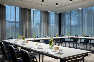 史基浦Renaissance Amsterdam Schiphol Airport Hotel的一间会议室,配有桌椅和大窗户