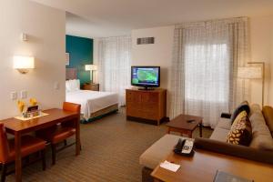 威奇托Residence Inn by Marriott Wichita East At Plazzio的酒店客房设有沙发、床和电视。