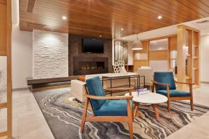 卡拉马祖Fairfield Inn & Suites by Marriott Kalamazoo的客厅配有桌椅和壁炉