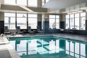 威克斯巴勒Residence Inn by Marriott Wilkes-Barre Arena的一座游泳池,里面设有桌椅和窗户