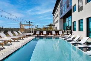 奥斯汀AC Hotel by Marriott Austin Hill Country的一座带躺椅的游泳池和一座建筑