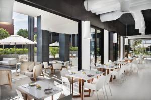 迪拜迪拜城市漫步傲途格精选酒店的餐厅设有白色的桌椅和大窗户。