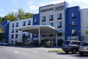 温斯顿·塞勒姆SpringHill Suites by Marriott Winston-Salem Hanes Mall的一座蓝色的大建筑,汽车停在停车场