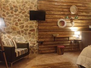 OítiΟ Σκίουρος Παραδοσιακοί Ξενώνες的一间配有沙发和电视的客房,拥有一堵石墙
