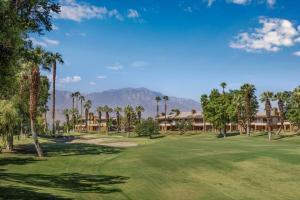 棕榈荒漠万豪沙漠泉别墅酒店的享有棕榈树和房屋的高尔夫球场的景色