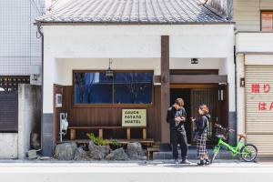 松本Couch Potato Hostel - Vacation STAY 88241的两个人站在一座建筑物前面,骑着一辆自行车