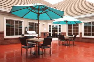 萨利纳斯Residence Inn by Marriott Salinas Monterey的天井配有2张桌子和椅子及遮阳伞