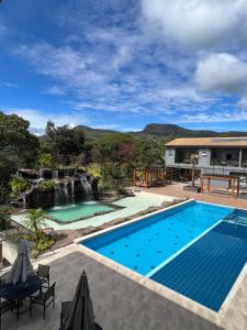卡皮托利乌Pousada do Batata的一个带瀑布的游泳池和一个度假村