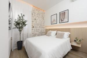 扎达尔NEW!Beautiful modern bedrooms and apt Old town Zadar- Great location的卧室配有一张白色的大床和石墙