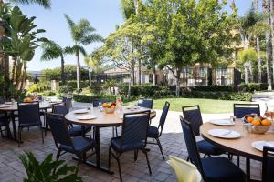 圣安娜梅萨海岸南海岸新城万怡酒店的户外庭院配有桌椅和树木。