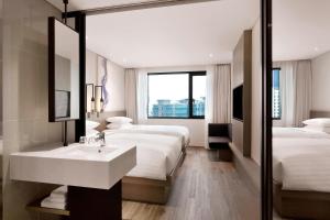 釜山Fairfield by Marriott Busan的酒店客房设有两张床、一个水槽和镜子