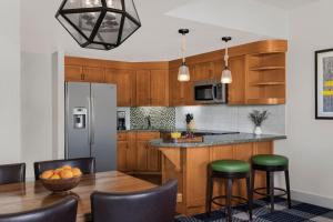 南太浩湖Marriott Grand Residence Club, Lake Tahoe的厨房配有木制橱柜和带绿色凳子的桌子。