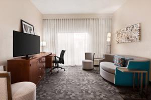 塔尔萨万豪塔尔萨中央庭院酒店的一间客厅,客厅配有沙发和电视,位于酒店的房间