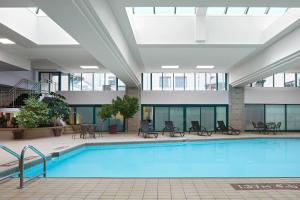 哈利法克斯哈利法克斯万豪港湾酒店的一座带桌椅的建筑中庭的游泳池
