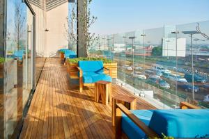 墨西哥城墨西哥城托雷奥万怡酒店的阳台设有蓝色椅子,享有城市美景。