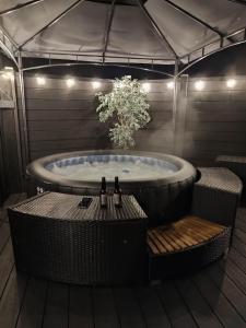 SwanlinbarThe POD Unique & Stylish Luxury Accommodation With Hot Tub的浴缸、桌子和2瓶葡萄酒