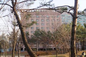 安山市奥拉酒店的前面有一堆树木的大建筑