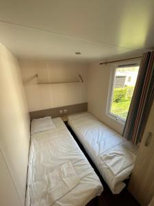 Saint-ChéronMobilHome 3 chambres 6 personnes Piscine Camping Saint Cheron的小型客房 - 带2张床和窗户