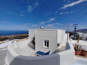 VourvoúlosWhite Swallow Suite Santorini的屋顶上设有两把蓝色椅子的白色房子