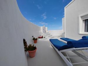 VourvoúlosWhite Swallow Suite Santorini的白色的客房拥有白色的墙壁和蓝色的天花板。