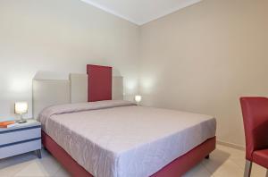 圣维托罗卡波吉卜力酒店的一间卧室配有一张床和一张红色椅子