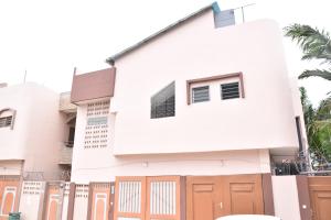 科托努Tranquillité Cotonou的白色的房子,有橙色的门和栅栏