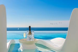 安德拉特斯Blue Sky Mallorca Luxury Villa的坐在海边的桌子上,放上一瓶葡萄酒