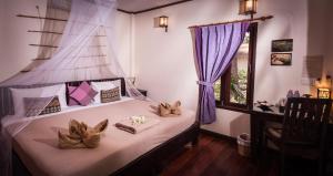 通萨拉班蒙拉里度假酒店的一间卧室配有一张带紫色窗帘的床和窗户。