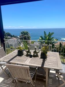 开普敦Villa del Mar - "Luxurious en-suite bedroom with lounge and stunning sea view balcony in Bantry Bay"的阳台上的木桌上摆放着盆栽植物