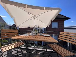 奥尔登堡Apartment in Uni- und Citynähe的阳台上配有带雨伞的木桌