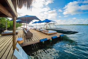 巴尔Hotel Agua Baru by Mustique的一个带椅子和遮阳伞的码头和水上船只