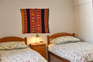 TorotoroHostal Margaritas Torotoro的卧室配有两张床,墙上挂着毯子。