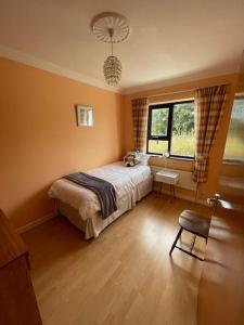 道宁斯Heather Hill Cottage的一间卧室设有一张床、一个窗口和一把椅子
