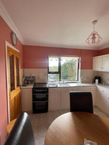 道宁斯Heather Hill Cottage的厨房设有红色的墙壁、桌子和炉灶。