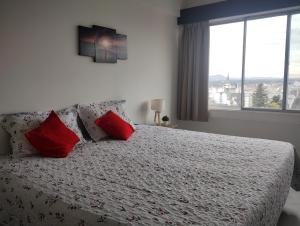 圣卡洛斯-德巴里洛切Mountain Center的一间卧室配有一张带红色枕头的床和一扇窗户
