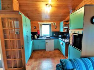 新卡姆诺克Glen Roe - 3 Bed Lodge on Friendly Farm Stay with Private Hot Tub的一间设有蓝色橱柜和窗户的小厨房