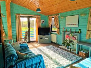 新卡姆诺克Glen Roe - 3 Bed Lodge on Friendly Farm Stay with Private Hot Tub的蓝色的客厅配有沙发和电视