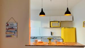卡波布里奥Studios Unamar的一个带两个盘子和黄色冰箱的厨房