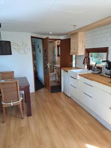 VledderKnusse chalet in een schitterende omgeving的厨房配有白色橱柜和木桌