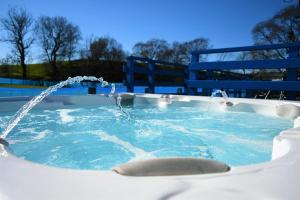 新卡姆诺克Glen Roe - 3 Bed Lodge on Friendly Farm Stay with Private Hot Tub的热水浴池设有2个喷泉和1个蓝色长椅