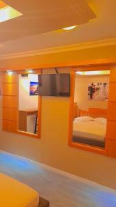 格拉玛多阿维尼达汽车旅馆（仅限成人入住）的一间卧室配有电视、一张床和镜子