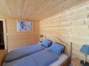 圣安特尼恩Sonja's Michelshof的一张位于木房的床位,里面挂着一张婴儿的照片