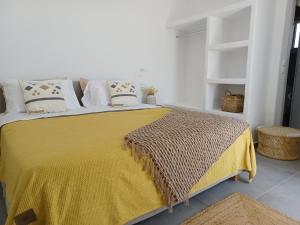 米克诺斯城Alko Apartments的一间卧室配有一张带黄色毯子和枕头的床。