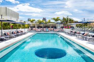 迈阿密海滩Moxy Miami South Beach的一座大楼内的游泳池,配有椅子和遮阳伞