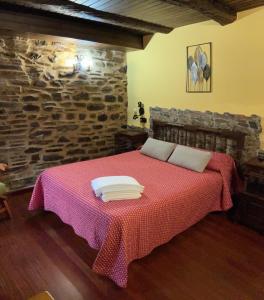 圣埃乌拉利亚德奥斯科斯Casa Freixe Apartamentos Rurales的一间卧室配有一张红色的床和石墙