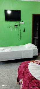诺布里斯Pousada Canto das Araras - Vila Bom Jardim Nobres MT的绿色的客房设有两张床和墙上的电视。
