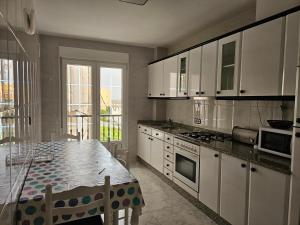 拉赫Apartamento en Laxe, Costa da Morte的厨房配有白色橱柜和桌子